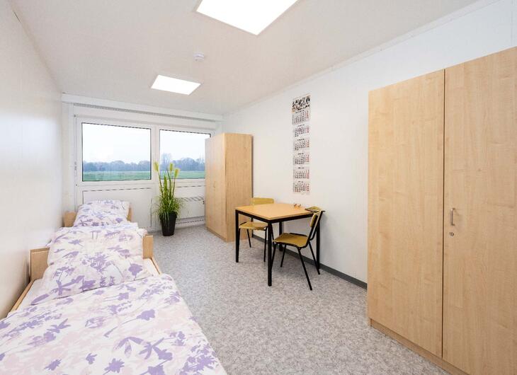 Wohncontainer mit zwei Betten, Schreibtisch und Schränken