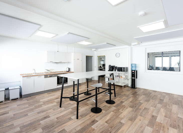 Container von innen mit Holzboden, Küche und Hochtisch mit Stühlen Container von innen mit Holzboden, Küche und Hochtisch mit Stühlen