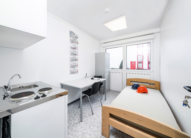 Wohncontainer Innenansicht mit Waschbecken, Bett und Schreibtisch