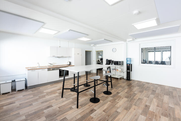 Container von innen mit Holzboden, Küche und Hochtisch mit Stühlen Container von innen mit Holzboden, Küche und Hochtisch mit Stühlen