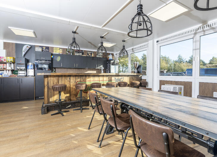 Aufenthaltsraum-innen-mit-Holztisch und Holz Stühlen