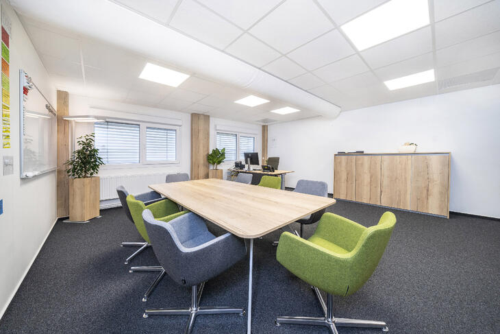 Besprechungsraum mit Filzboden, Tisch, Stühlen und Schreibtisch