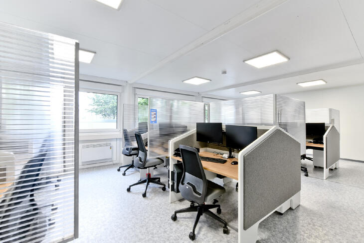 Bürocontainer von innen mit ausgestatteten Tischen und Trennwänden
