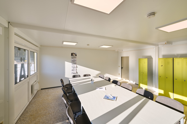 Lyst mødelokale med bord og stole