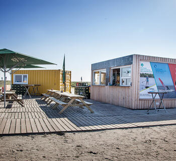 Strandkiosk med bænke og parasoller foran