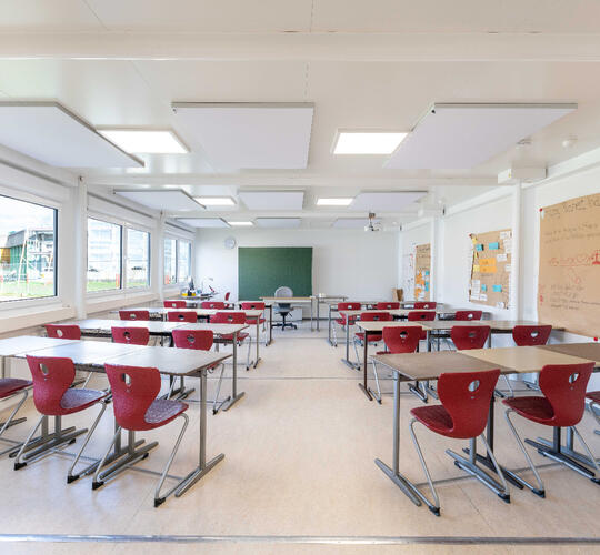 Stort klasselokale med borde og røde stole