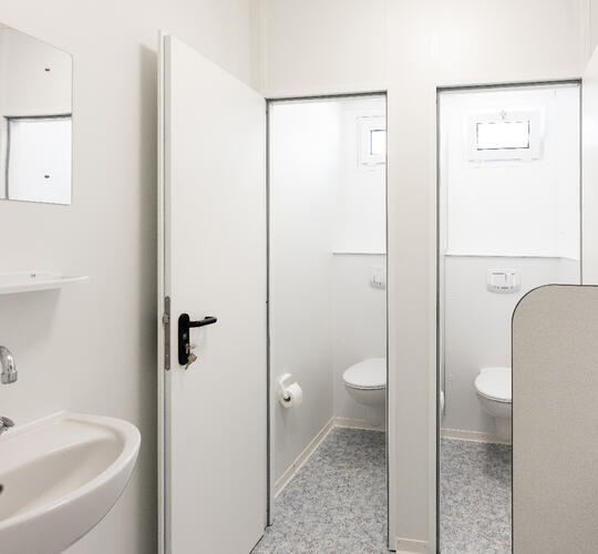 Sanitetsmodul indefra med to toiletter i fokus.