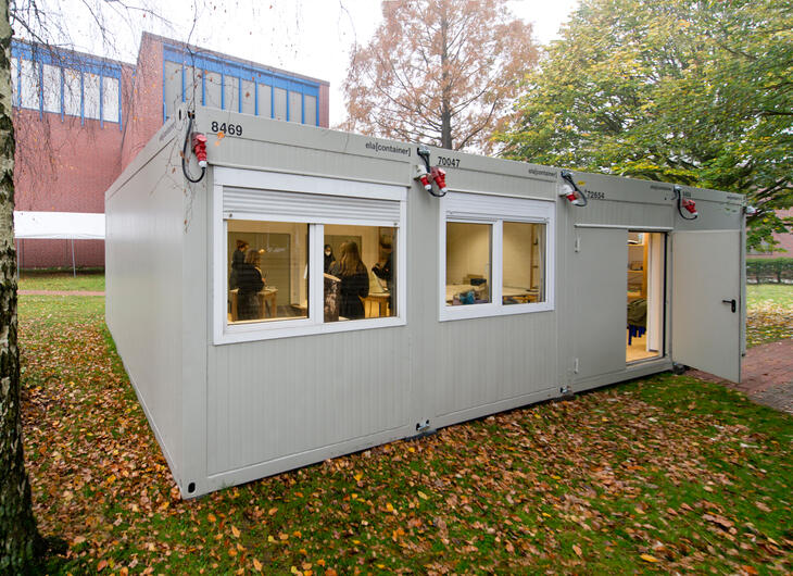 Lille skolebygning med vinduer og åben dør