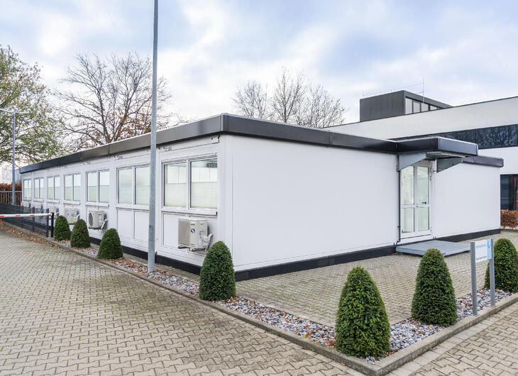 Hvide skolemoduler med sorte kanter, der matcher skolens hovedbygning