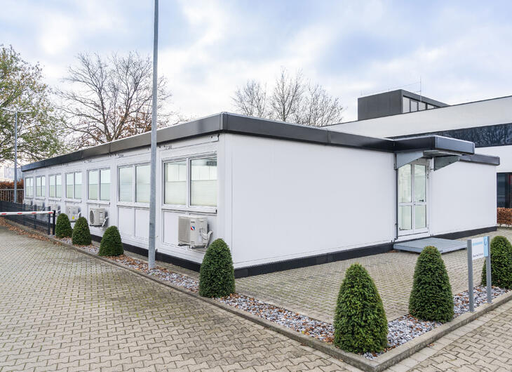 Hvid modulbygning med sorte kanter, der matcher hovedbygningen