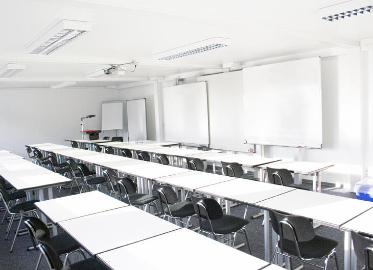 Klasselokale med lange rækker af pulte og stole