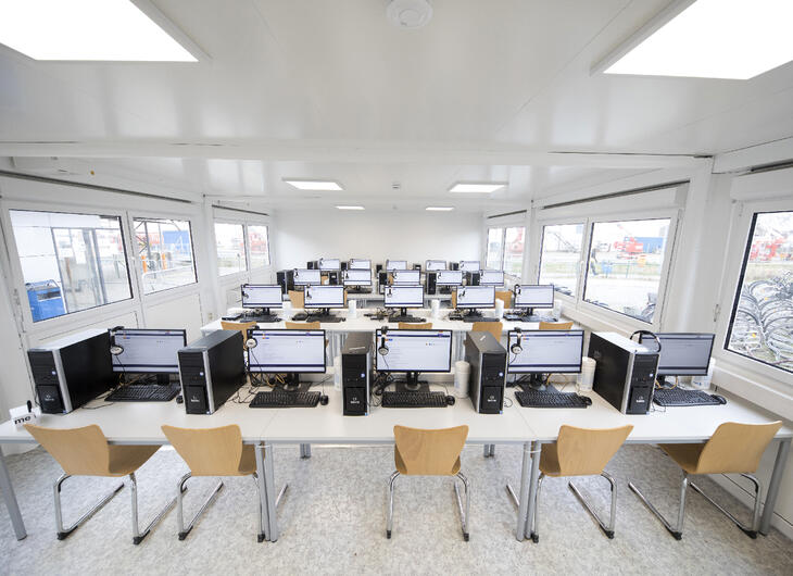 Undervisningslokale med borde, stole og computere