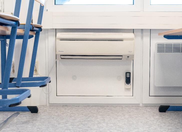 Vægmonteret aircondition og radiatorer under vinduerne i et klasselokale