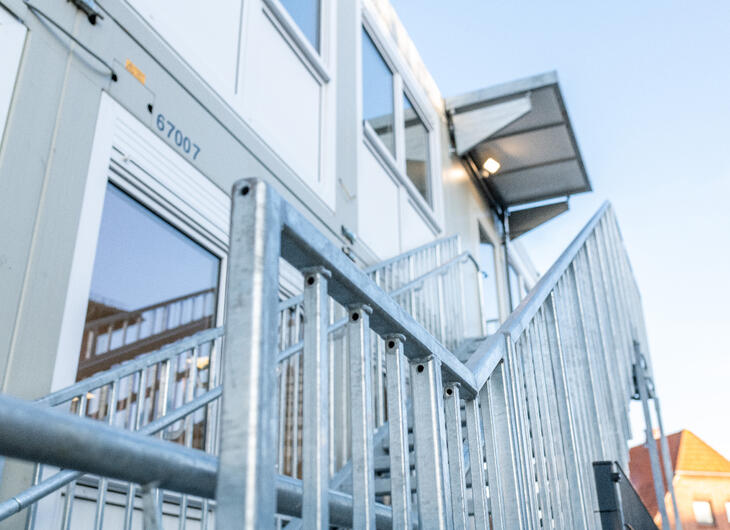 Udvendig trappe, der fører op til indgang med tagudhæng