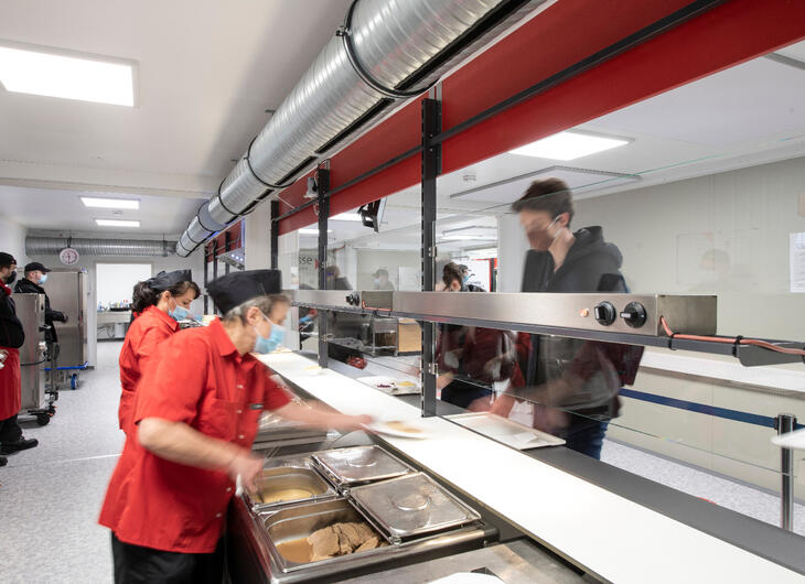 Serveringspersonale, der serverer frokost over disken