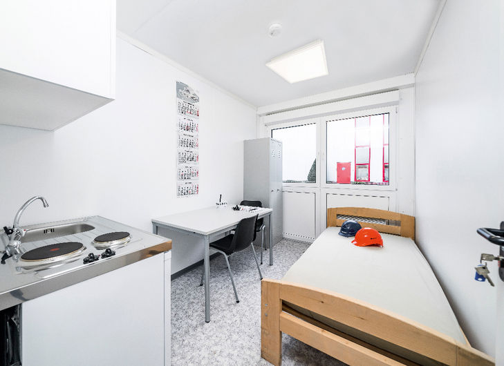 Indersiden af en boligmodul med seng, bord og stole