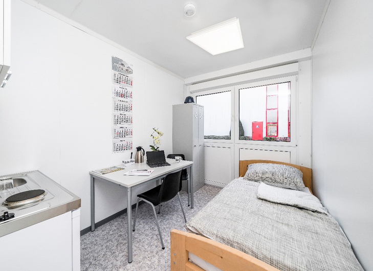 Boligmodul med tekøkken, seng, skabe, bord og stole