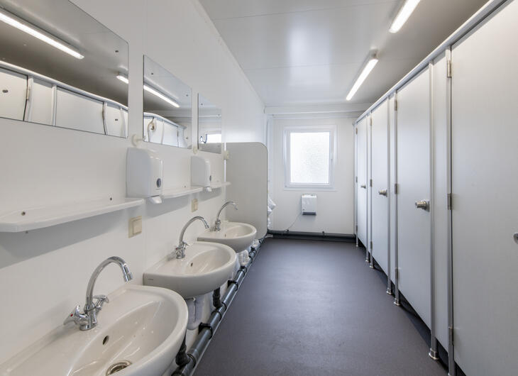Lys toiletcontainer med toiletkabiner og håndvaske