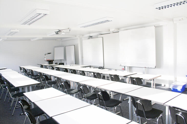 Innenansicht Klassenzimmer Schulcontainer mit weißen Tischen und schwarzen Stühlen - ELA Container
