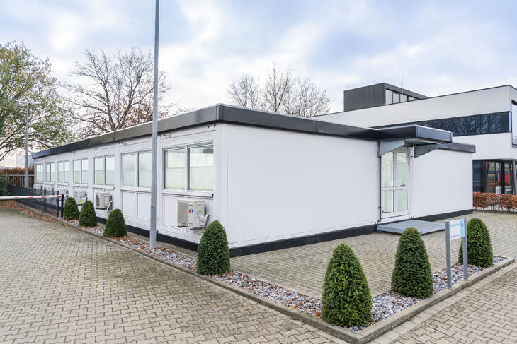 Hvid modulbygning med sorte kanter, der matcher hovedbygningen