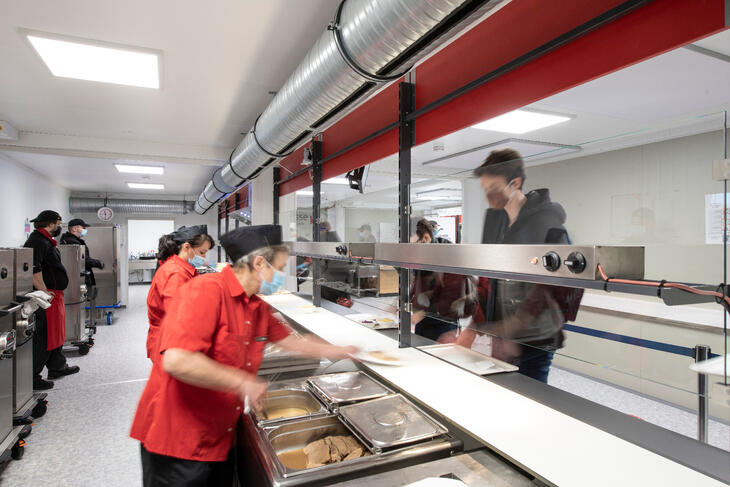 Serveringspersonale, der serverer frokost over disken