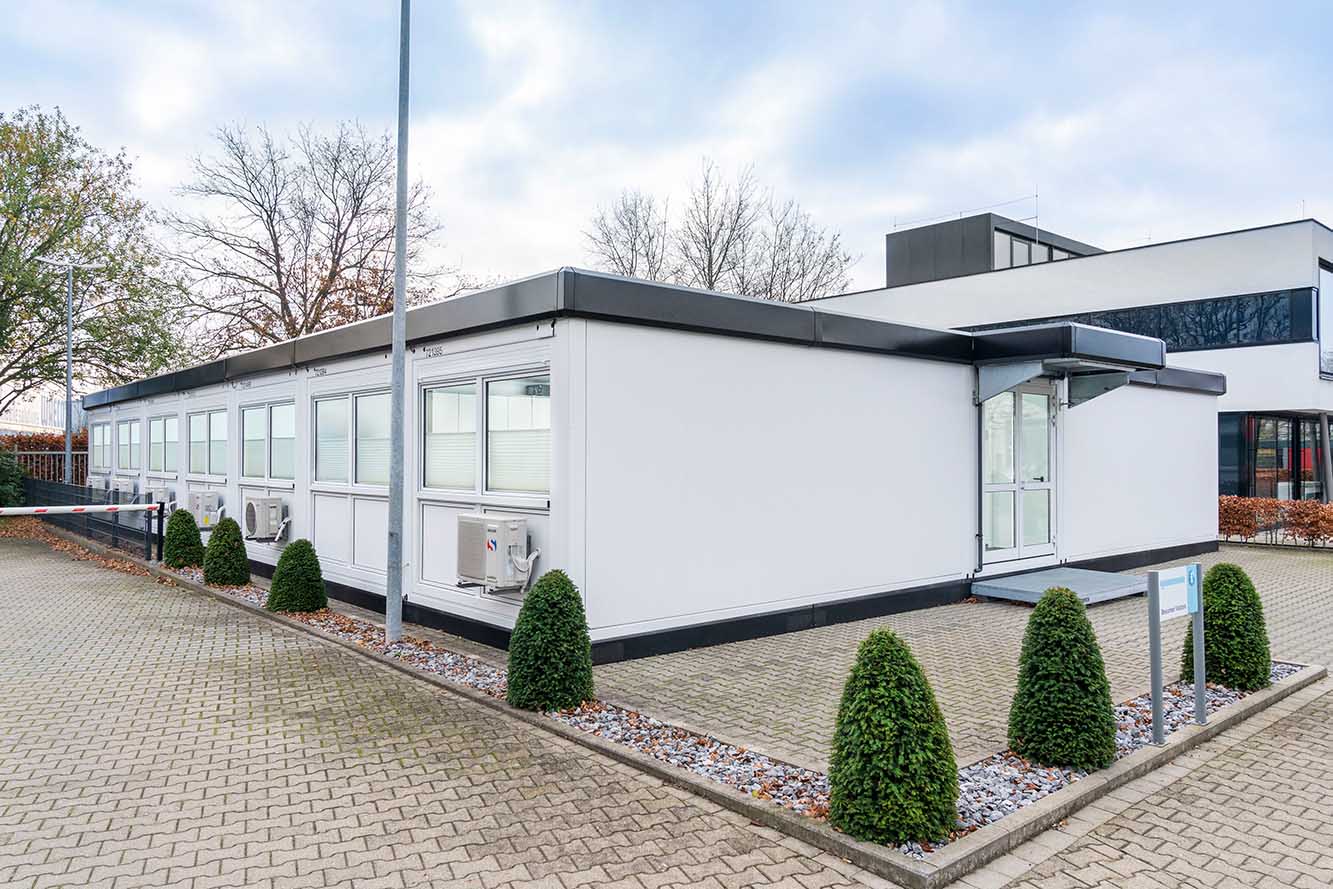 Modulanläggning i vitt med svart ram, matchande originalbyggnaden