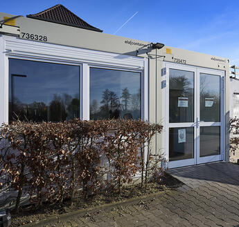 Ljusgrå restaurangmodul med stora fönsterpartier