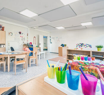 Insidan av en förskola med bord, stolar och färgglad inredning
