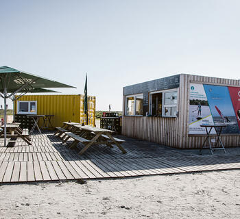 Strandkiosk med bänkar och parasoll framför