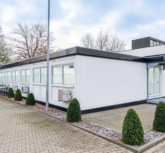 Modulanläggning i vitt med svart ram, matchande originalbyggnaden