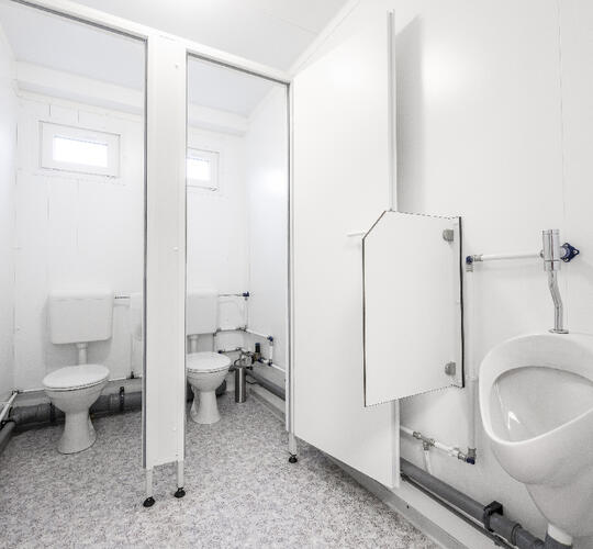 Sanitetsmodul med två toalettbås och en urinoar
