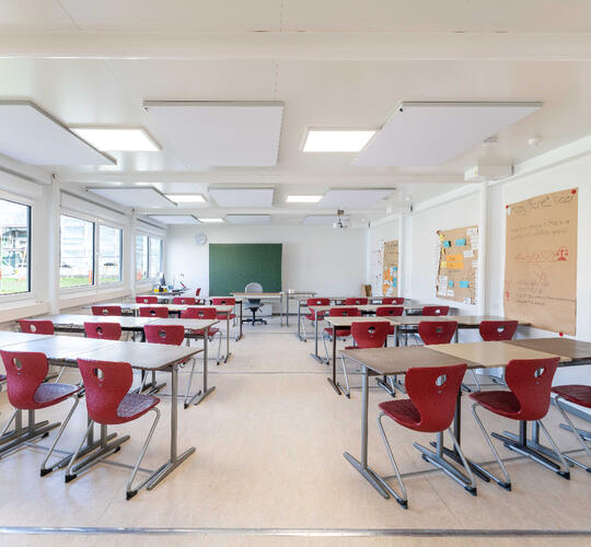 Stort klassrum med bord och röda stolar
