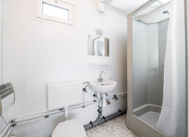 Enkelt badrum med toalett, vask och dusch