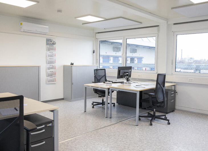 Arbetsrum med flera arbetsplatser bestående av skrivbord och stolar Arbetsrum med flera arbetsplatser bestående av skrivbord och stolar