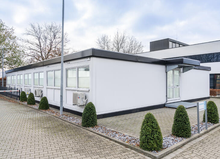 Vita skolmoduler med svarta kanter som matchar skolans huvudbyggnad Vita skolmoduler med svarta kanter som matchar skolans huvudbyggnad