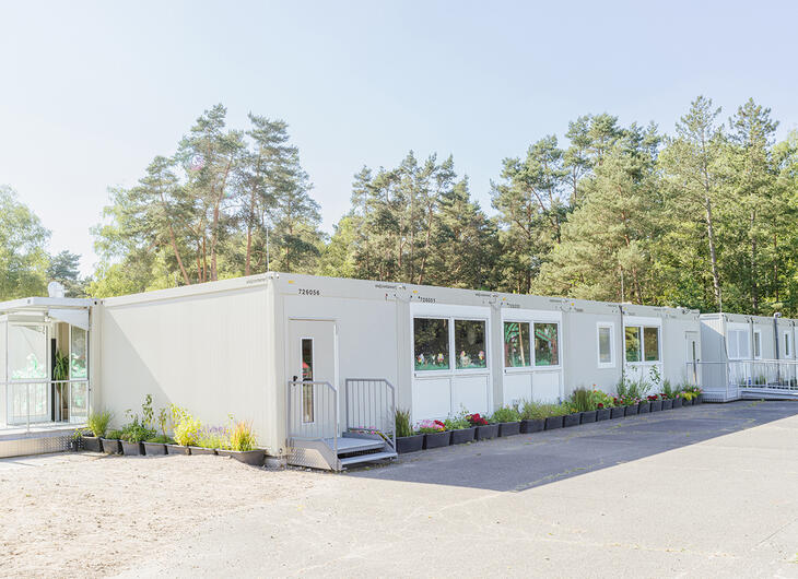 Mellanstor skolanläggning med flera ingångar och blomkrukor runt om Mellanstor skolanläggning med flera ingångar och blomkrukor runt om
