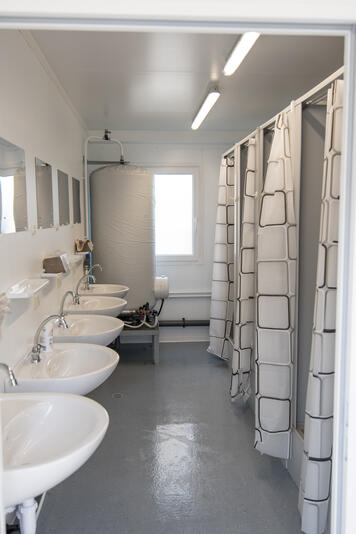 Sanitetsmodul med handfat och duschbås med draperi