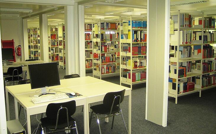 Större bibliotek med hyllor av böcker samt studieplatser Större bibliotek med hyllor av böcker samt studieplatser