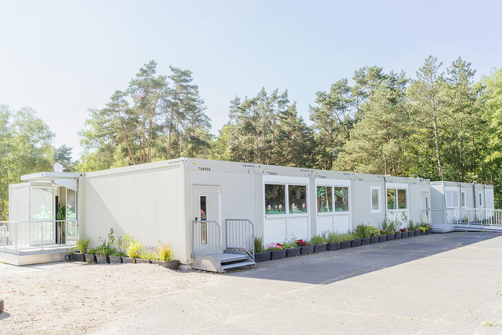 Mellanstor skolanläggning med flera ingångar och blomkrukor runt om Mellanstor skolanläggning med flera ingångar och blomkrukor runt om