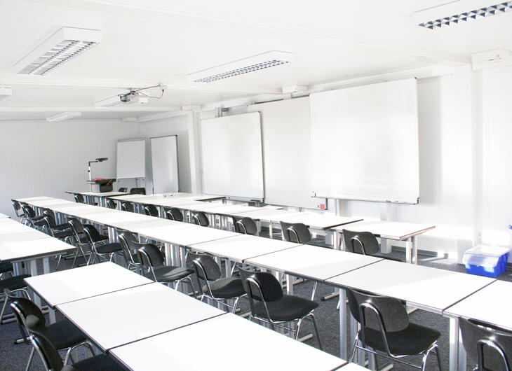 Innenansicht Klassenzimmer Schulcontainer mit weißen Tischen und schwarzen Stühlen - ELA Container