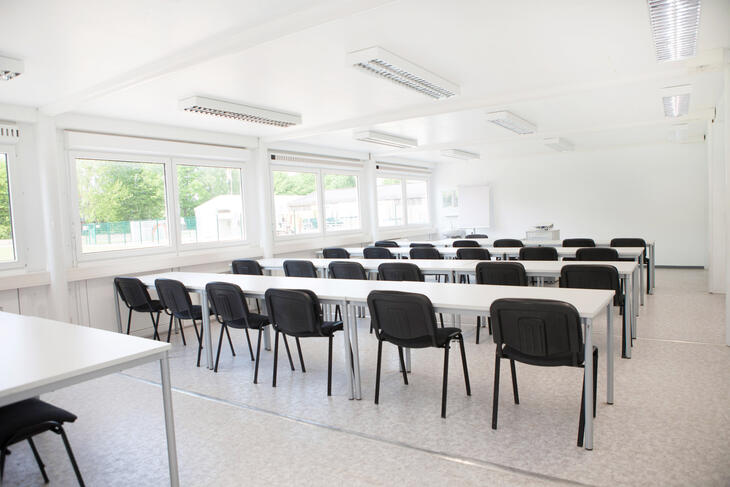 Innenansicht Klassenzimmer Schulcontainer mit weißen Tischen und schwarzen Stühlen - ELA Container
